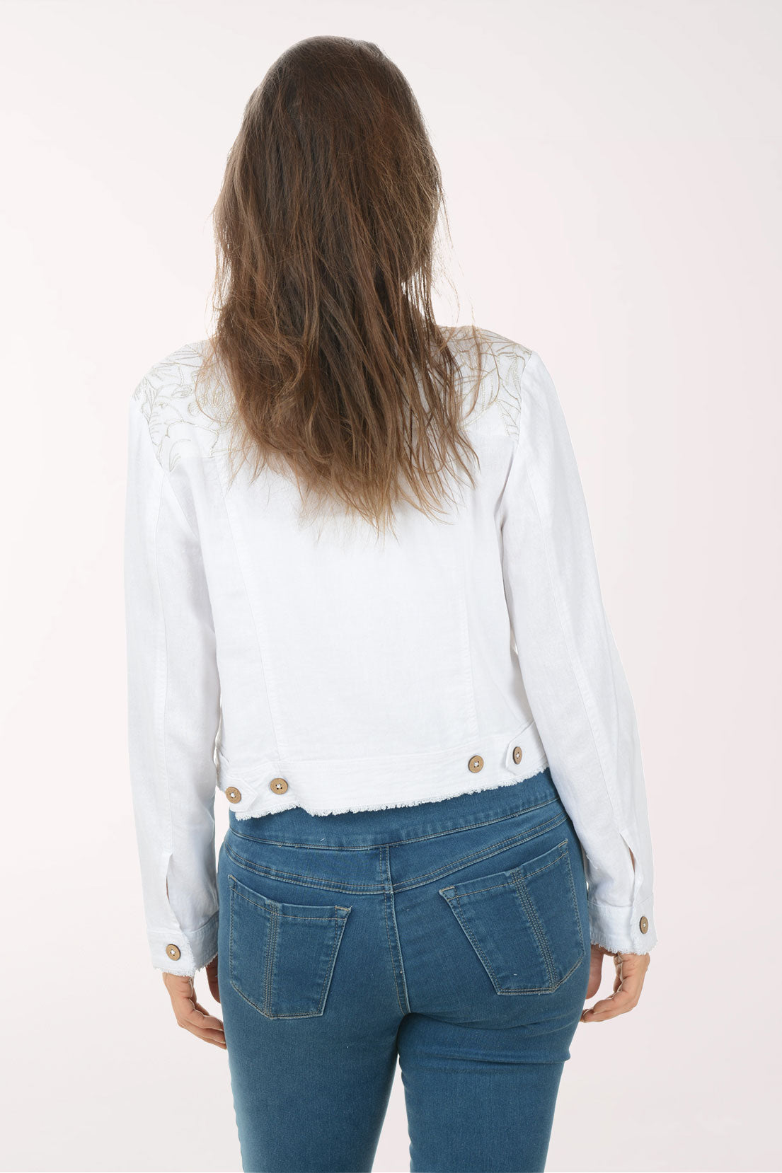 Woman wearing a white denim jacket with gold buttons on a white background