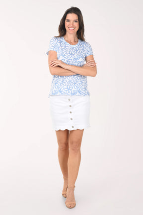 Woman wearing a blue patterned top and white skirt on a white background