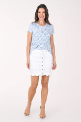 Woman wearing a blue patterned top and white skirt on a white background