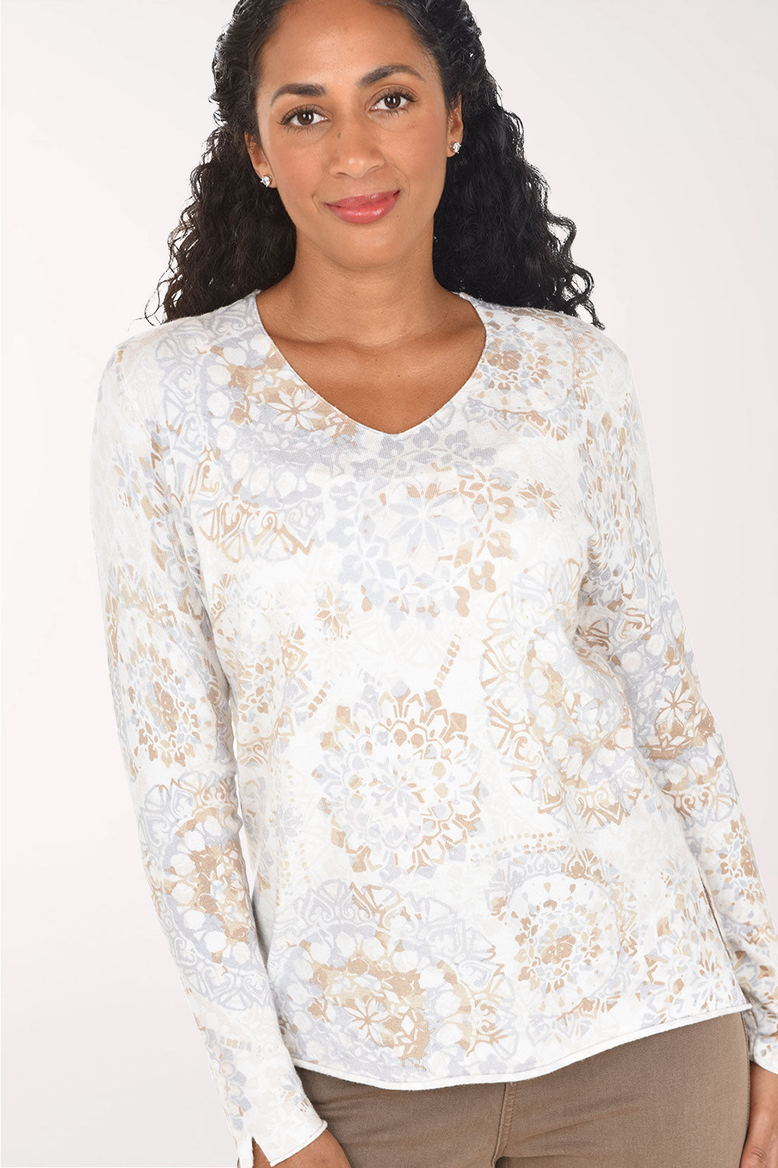 Woman wearing a long sleeve white sweater with a paisley print 