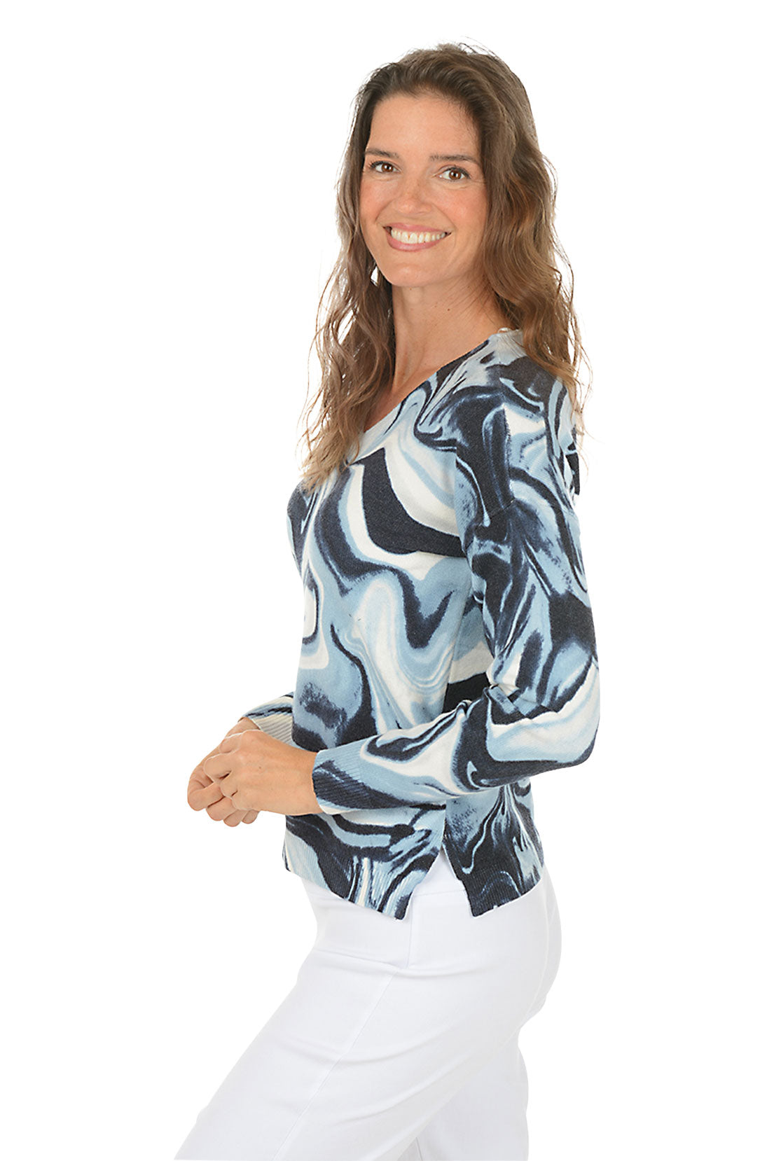 Woman wearing a blue and white marbled long-sleeve sweater on a white background. Side shot.