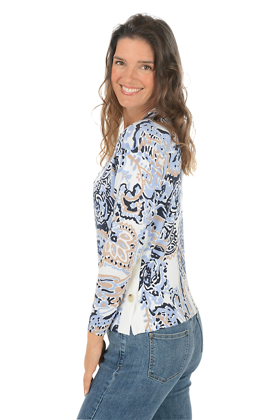 Woman wearing a blue paisley patterned sweater and jeans on a white background. Side shot.