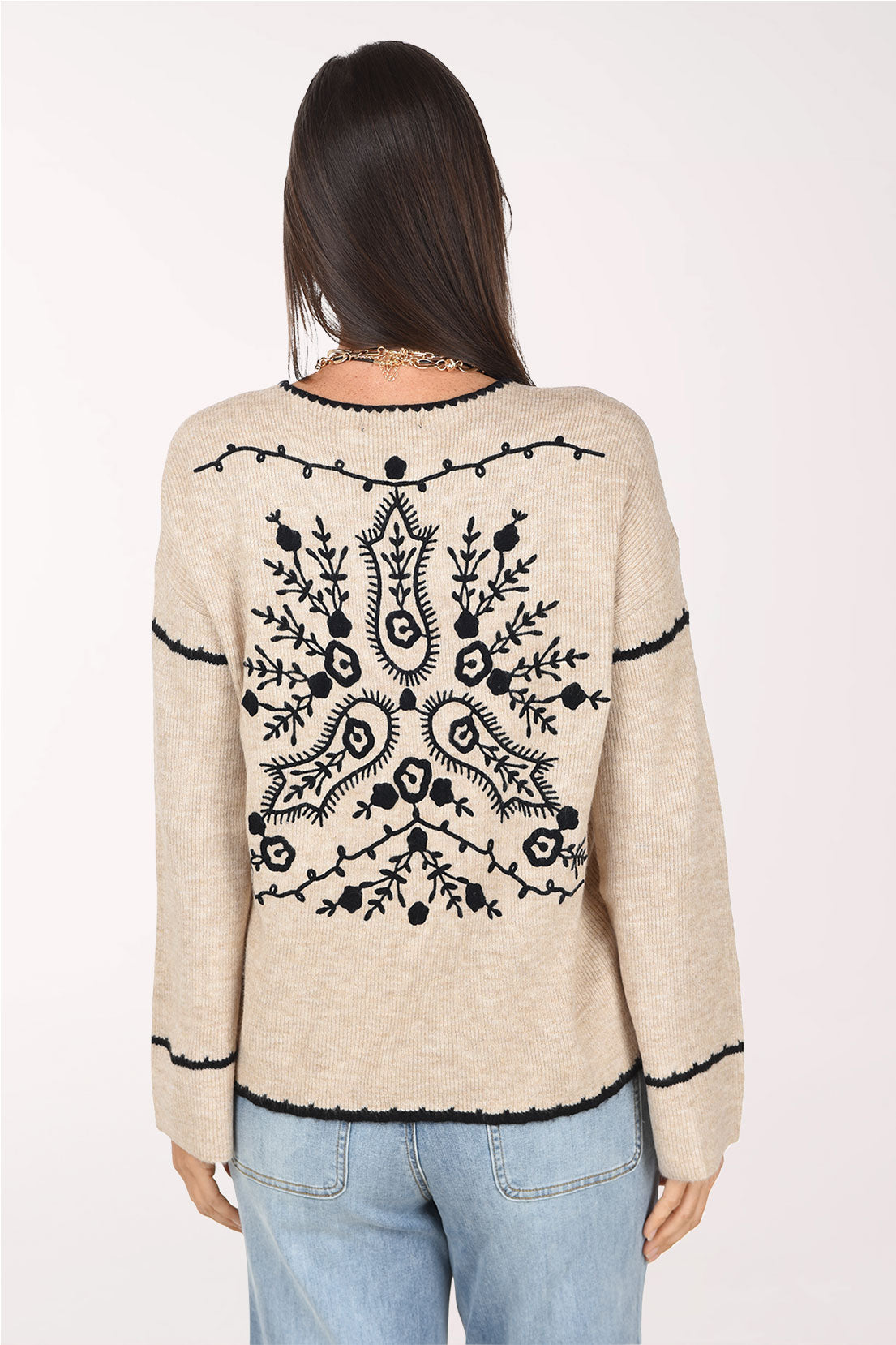 A back view of the almond sweater showing a large black embroidered floral design across the back.
