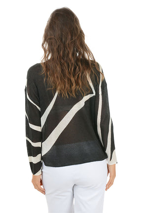 Woman wearing a black and white patterned sweater on a white background. Back shot.