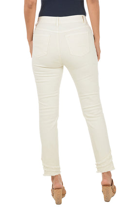 A woman wearing a beige ankle pant with three tiers of fringe on the hemline. Back shot.