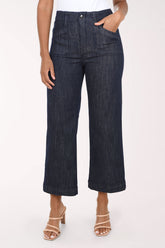 A model wearing dark wash cropped wide-leg denim jeans with a white top and beige heeled sandals, shown from the waist down against a plain white studio background.