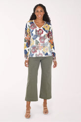A model wearing olive green cropped wide-leg jeans with a white top and beige heeled sandals, shown from the waist down against a light studio background.