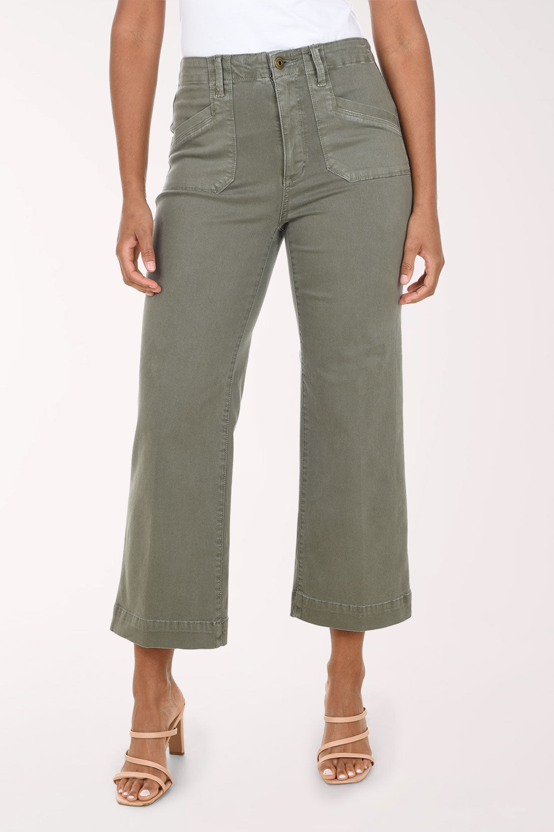 A model wearing olive green cropped wide-leg jeans with a white top and beige heeled sandals, shown from the waist down against a light studio background.