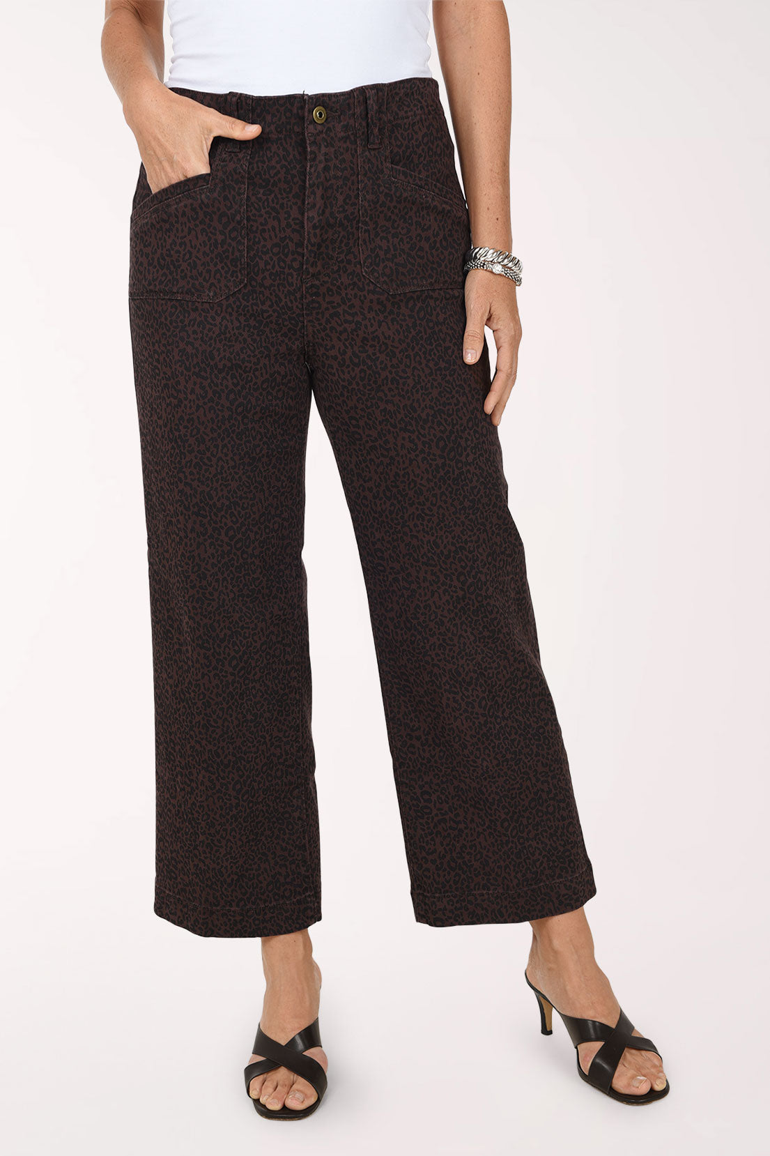 A front view of brown and black leopard print wide leg cropped jeans with front patch pockets, worn with a white top and black heeled sandals.