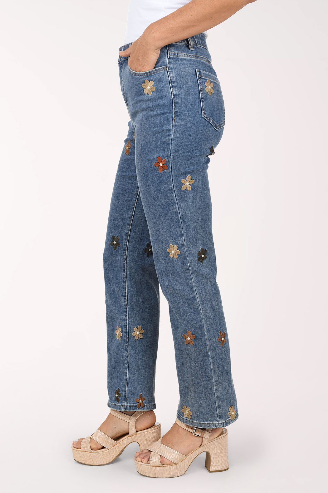 A side view of the embroidered flower straight leg jeans with a hand in the front pocket.
