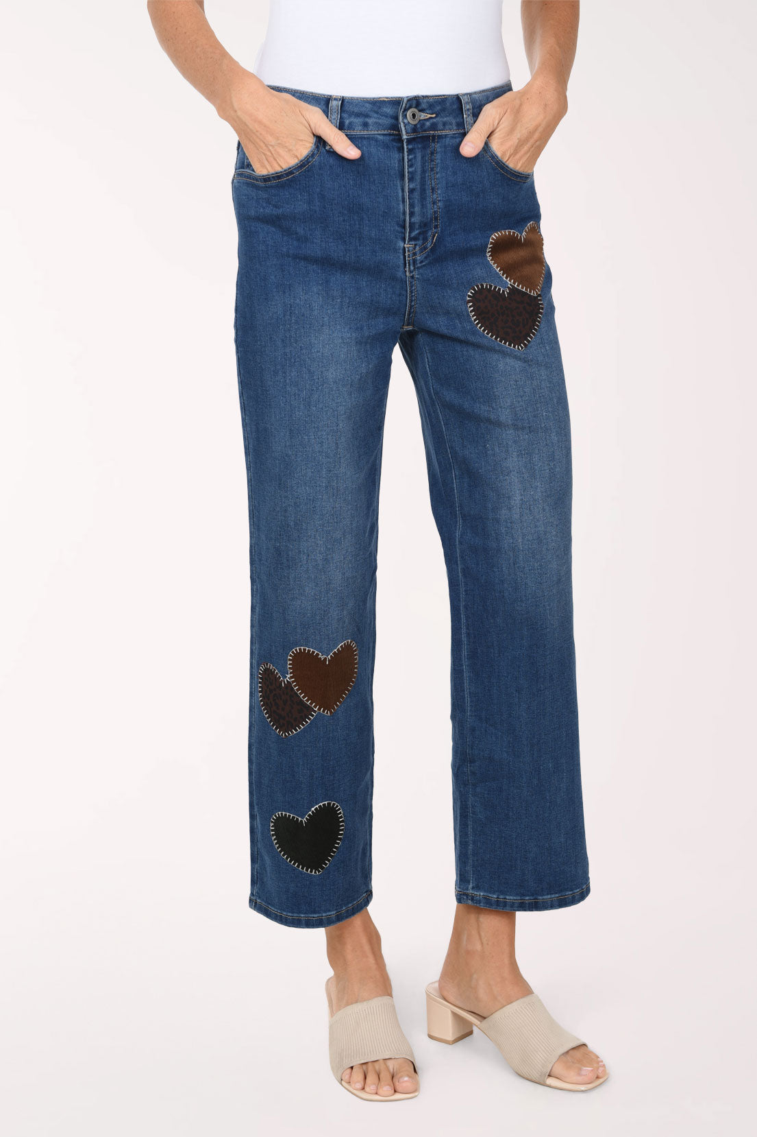 A front view of the heart patch straight leg jeans with a hand in the front pocket, showing hearts on the thigh and knee.