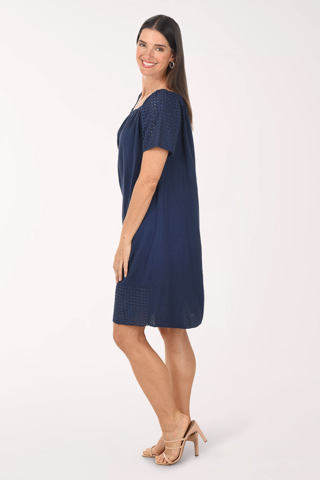 Woman wearing a navy blue dress with lace details on a white background