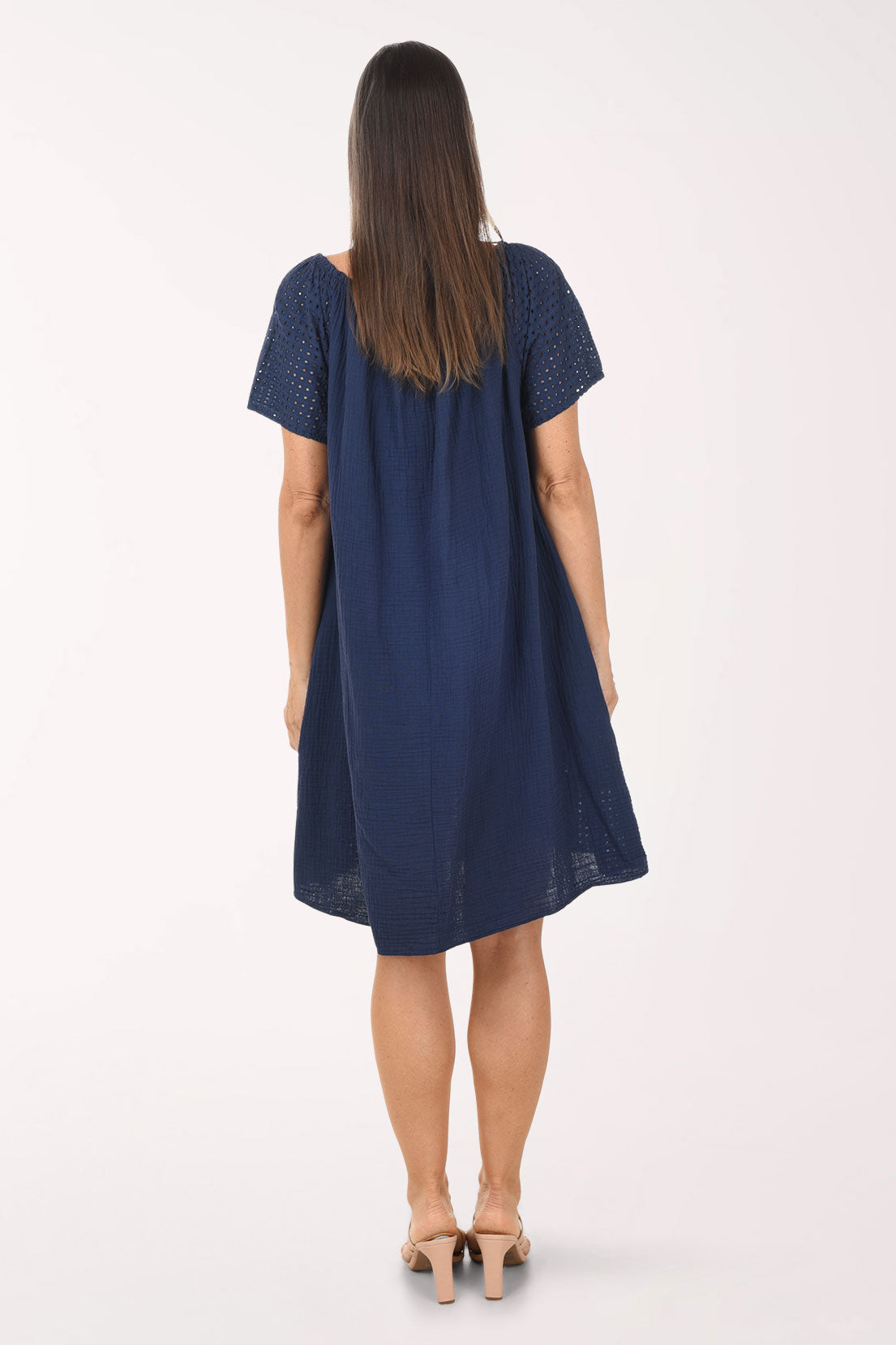 Woman wearing a navy blue dress with lace details on a white background