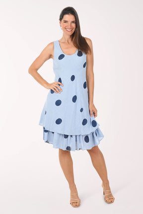 Woman wearing a light blue dress with dark polka dots on a white background