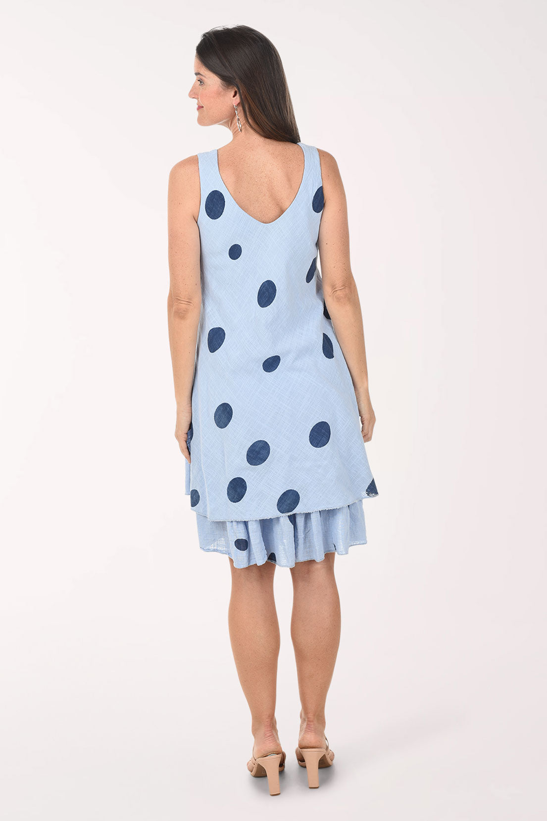 Woman wearing a light blue dress with dark polka dots on a white background