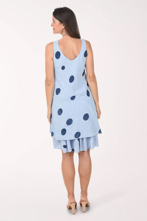 Woman wearing a light blue dress with dark polka dots on a white background