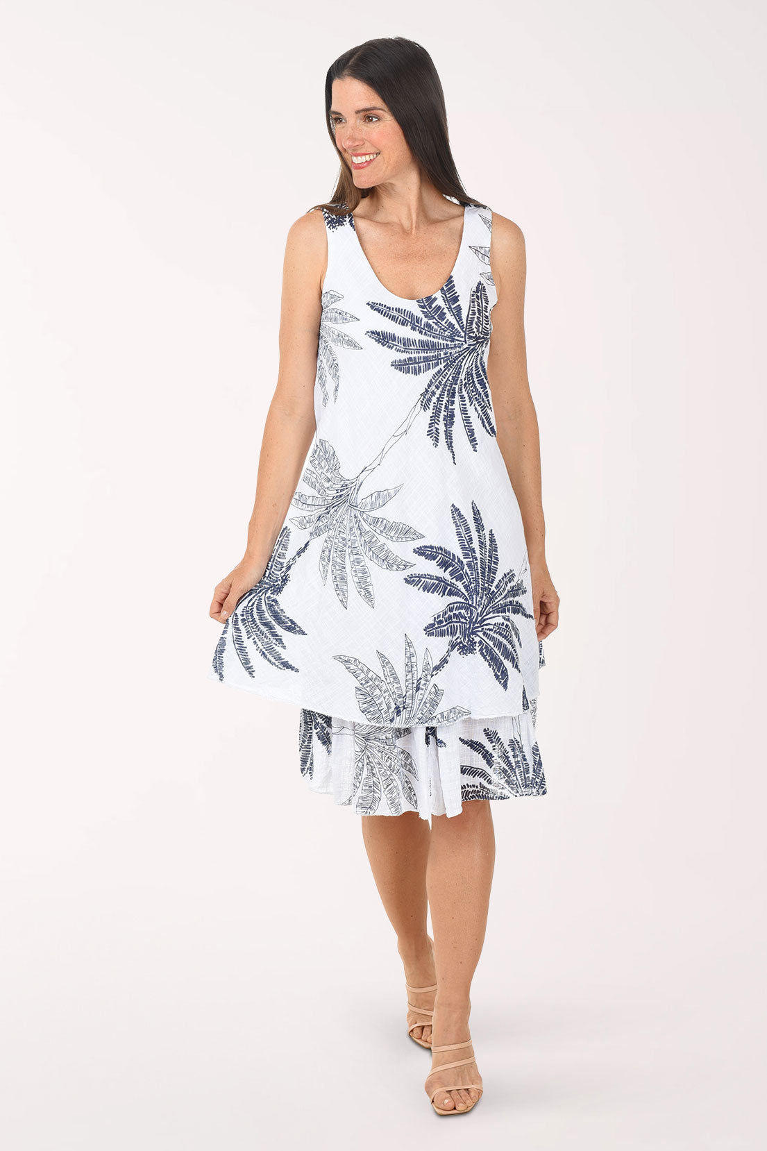 Woman wearing a white dress with blue palm tree patterns on a white background