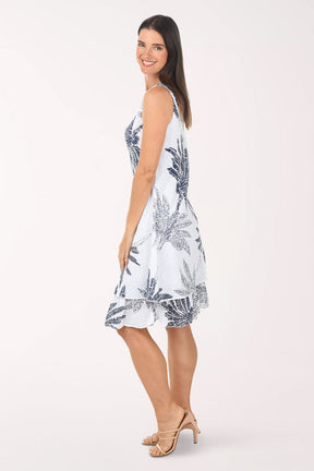 Woman wearing a white dress with blue palm tree patterns on a white background