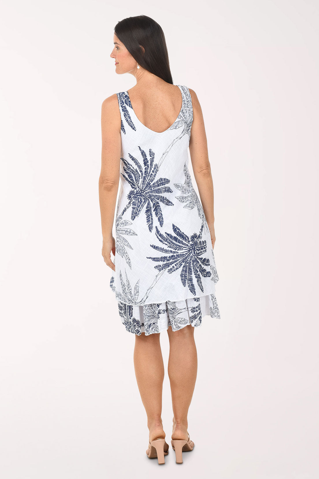 Woman wearing a white dress with blue palm tree patterns on a white background
