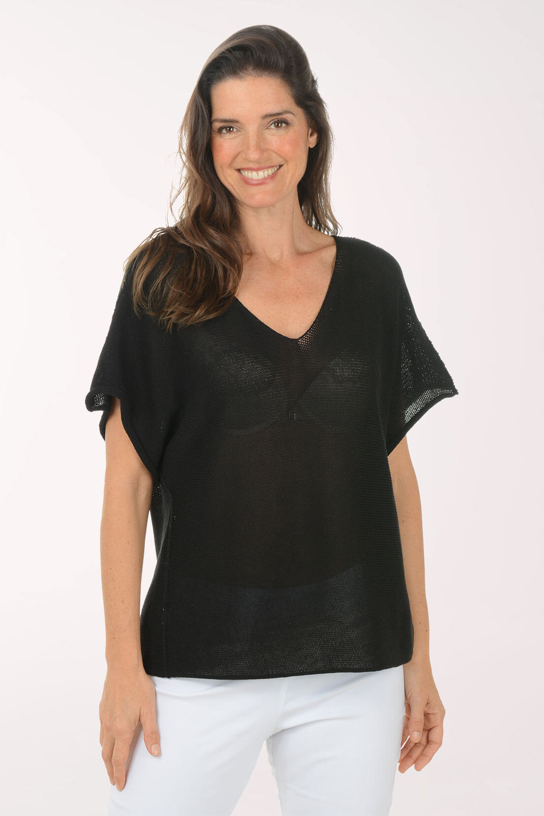 Woman wearing a black top and white pants on a white background