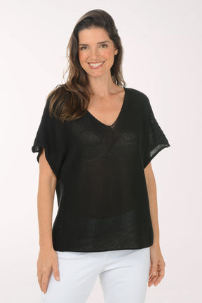 Woman wearing a black top and white pants on a white background