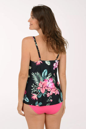 Woman wearing a black floral tank top and pink shorts on a white background. Back shot.