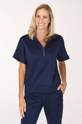 Front view of a woman in a navy Jet Blue scuba knit half zip top with a spread collar, silver zipper, short cuffed dolman sleeves and a straight hem, worn with matching navy pants.