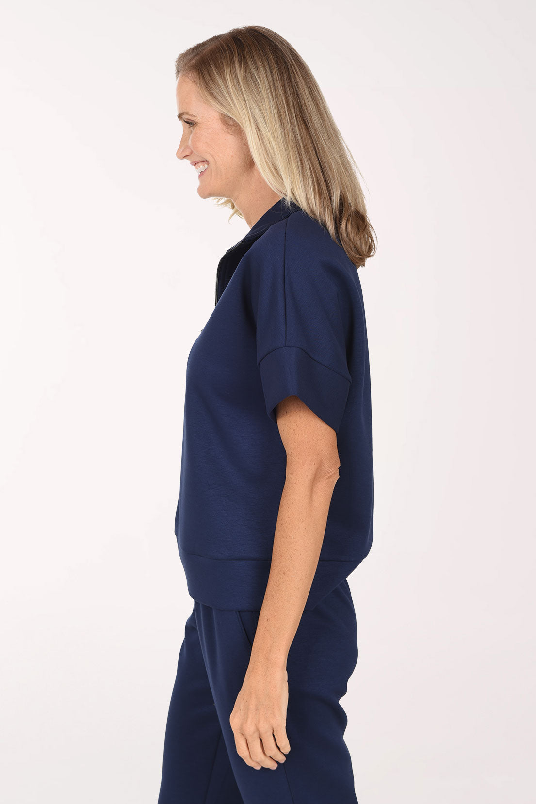 Side view of the navy Jet Blue scuba half zip top showing the short dolman sleeve with cuff and the straight hip-length hem.