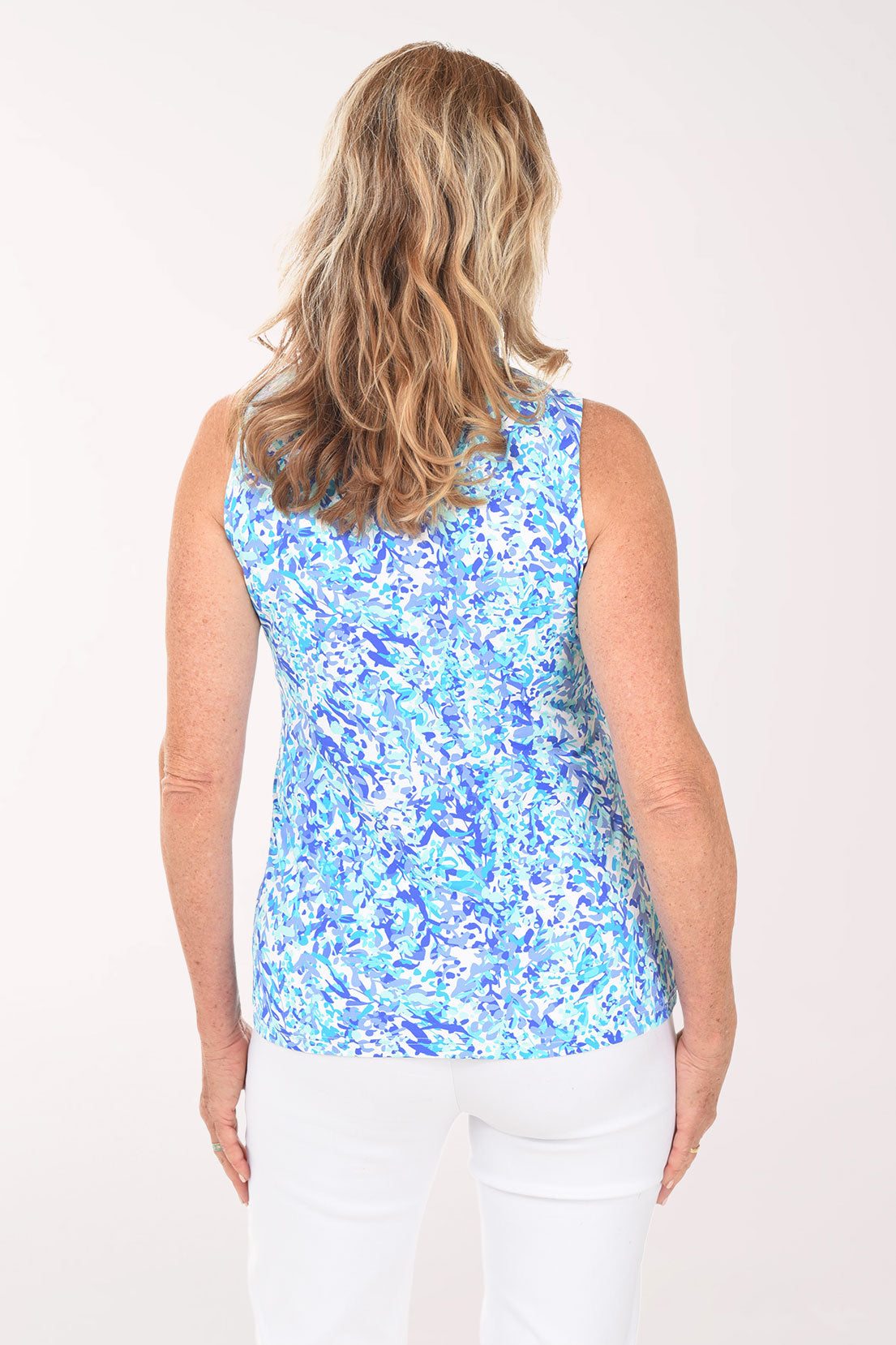 Woman wearing a blue floral sleeveless top against a white background