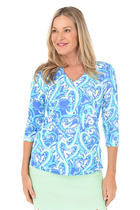 A woman wearing a blue heart patterned v-neck top with 3/4 sleeves.