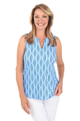 A woman wearing a sleeveless knit top with a split v-neckline and curved hemline, in a blue and white geometric pattern.