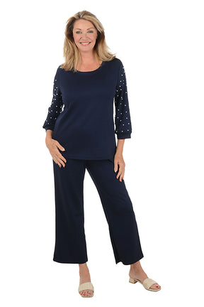 Woman wearing a navy outfit with embellished sleeves on a white background.