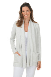 Woman wearing a light gray cardigan over a white top and pants on a white background.
