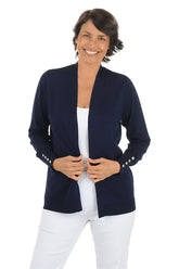 Woman wearing a navy cardigan with white pants on a white background.