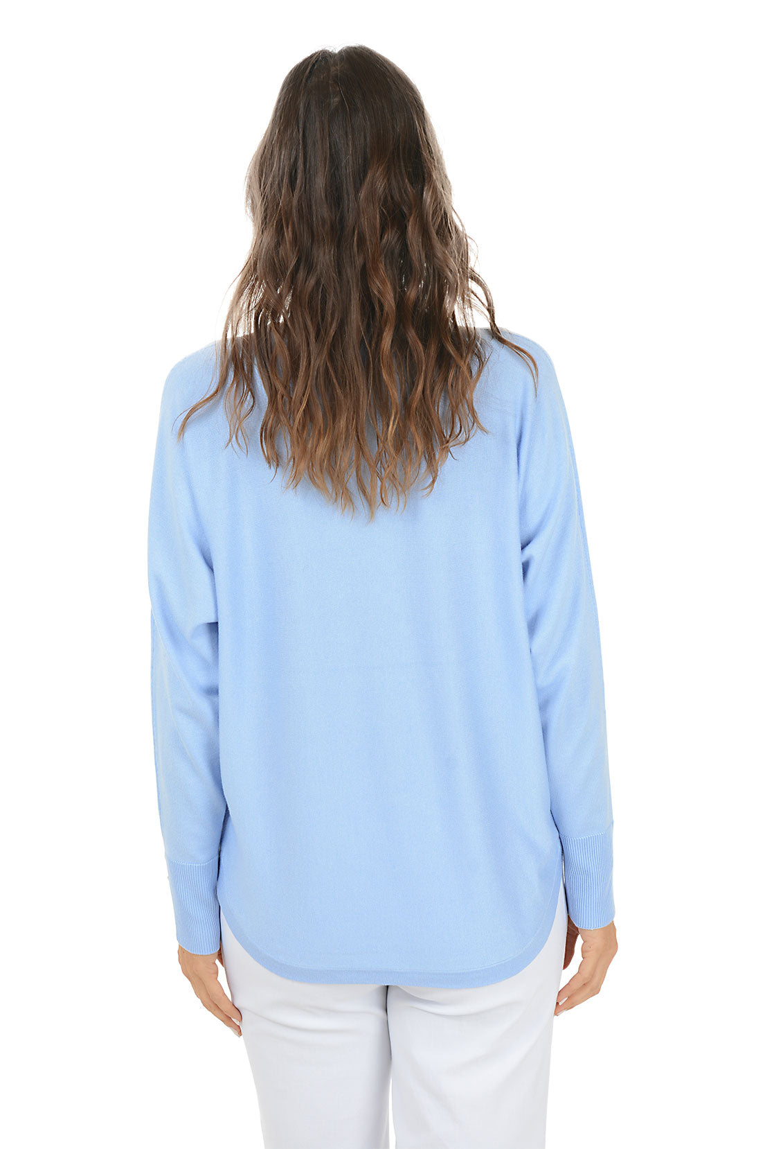 Woman wearing a light blue sweater and white pants on a white background. Back shot.