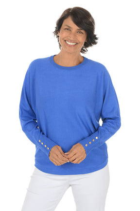 Woman wearing a blue sweater with gold buttons on a white background.