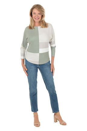 Woman wearing a color-blocked top and jeans on a white background.