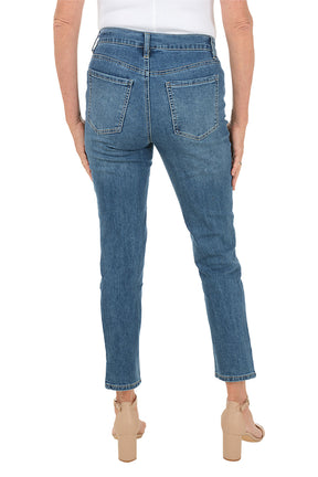 Blue denim ankle jeans worn by a person on a white background. Back shot.