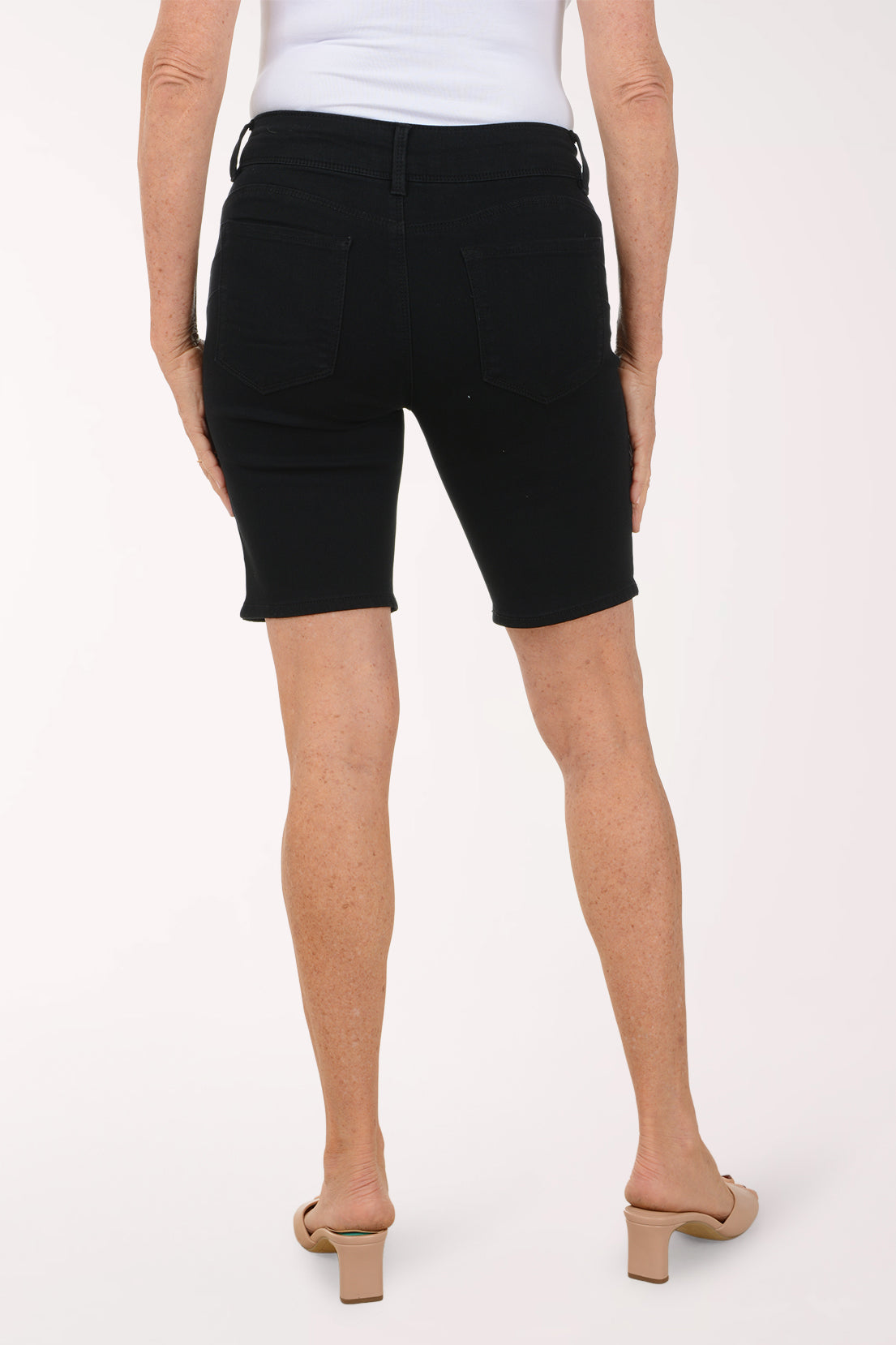 Person wearing black denim shorts on a white background