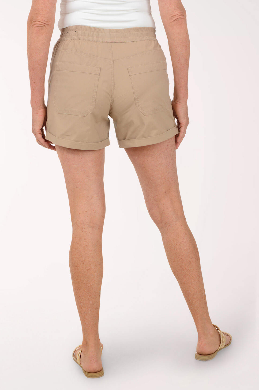 Beige shorts worn by a person on a white background