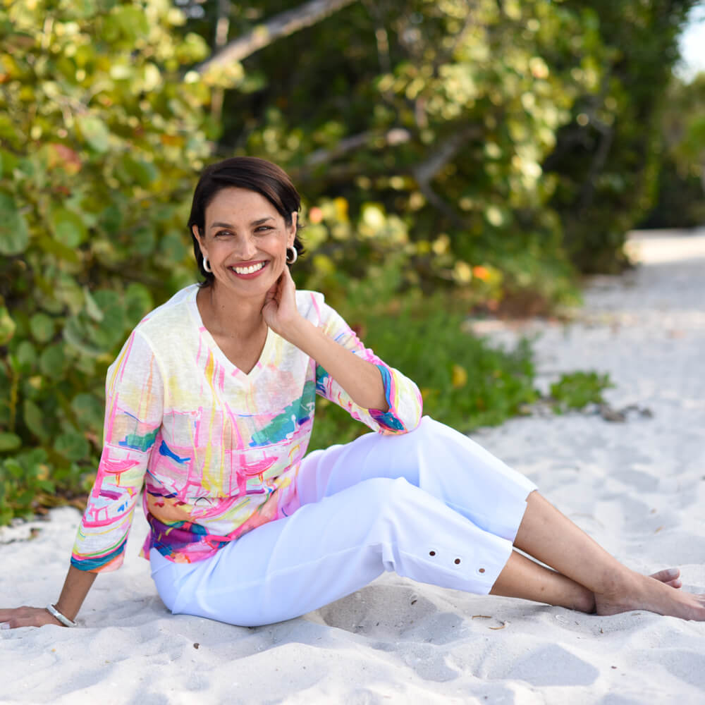 Woman sitting on a sandy path with greenery in the background