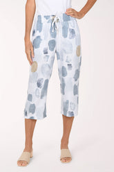 Woman wearing white crop pants with a blue and beige stone pattern