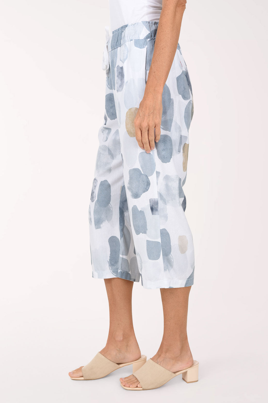 Woman wearing white crop pants with a blue and beige stone pattern
