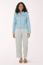 Woman wearing a light blue denim jacket and striped pants on a white background