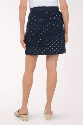 Person wearing a navy skirt with white polka dots on a white background
