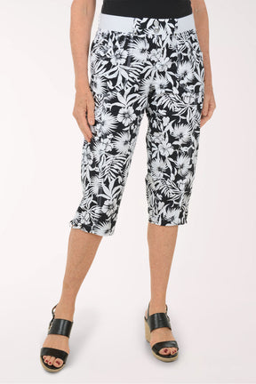 Woman wearing black and white leaf printed capri pants.