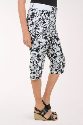 Woman wearing black and white leaf printed capri pants.