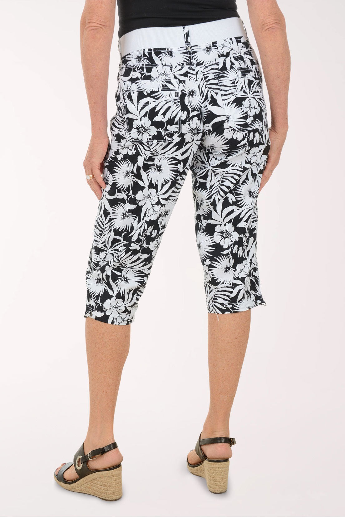 Woman wearing black and white leaf printed capri pants.