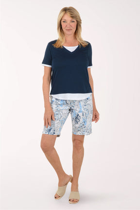 Woman wearing a navy blue top and patterned shorts on a white background
