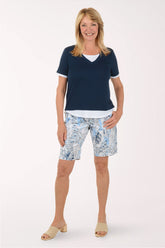 Woman wearing a navy blue top and patterned shorts on a white background